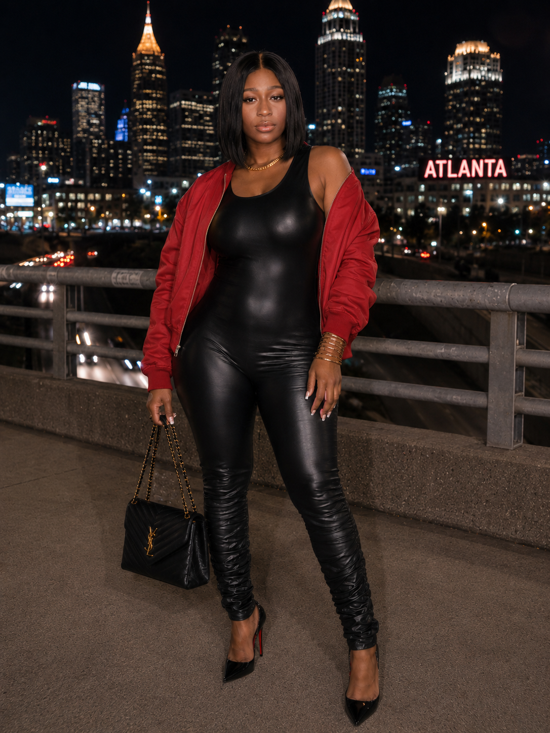 Woman in black leather outfit with red jacket against Atlanta skyline at night